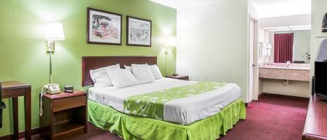 A hotel room with a bed, bedside lamps, a telephone, a mirror, and a television.