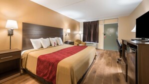 A hotel room with a large bed, bedside tables, a desk, a chair, a television, and a sliding door. - Econo Lodge Cullman South (Cullman)