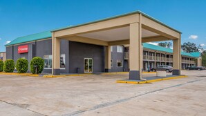 A motel with a covered parking area, a signboard, and a building with a green roof. - Econo Lodge Cullman South (Cullman)