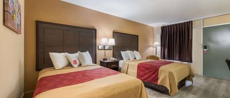 A hotel room with two beds, a nightstand with lamps, a door, and a wall-mounted artwork.