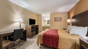 Ein Hotelzimmer mit Bett, Schreibtisch, Stuhl, Fernseher und einem durchgegangenen Tür sichtbaren Badezimmer.