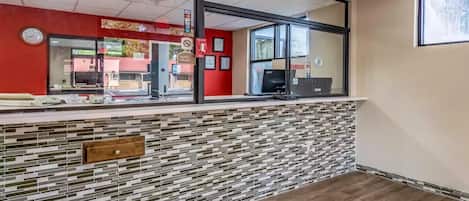 A reception area with a tiled wall, a clock, and a window with a view of the outside.