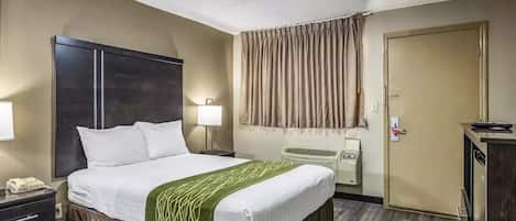 Una habitación de hotel con una cama grande, lámparas de noche, un armario, un escritorio con teléfono y una puerta con cerradura.