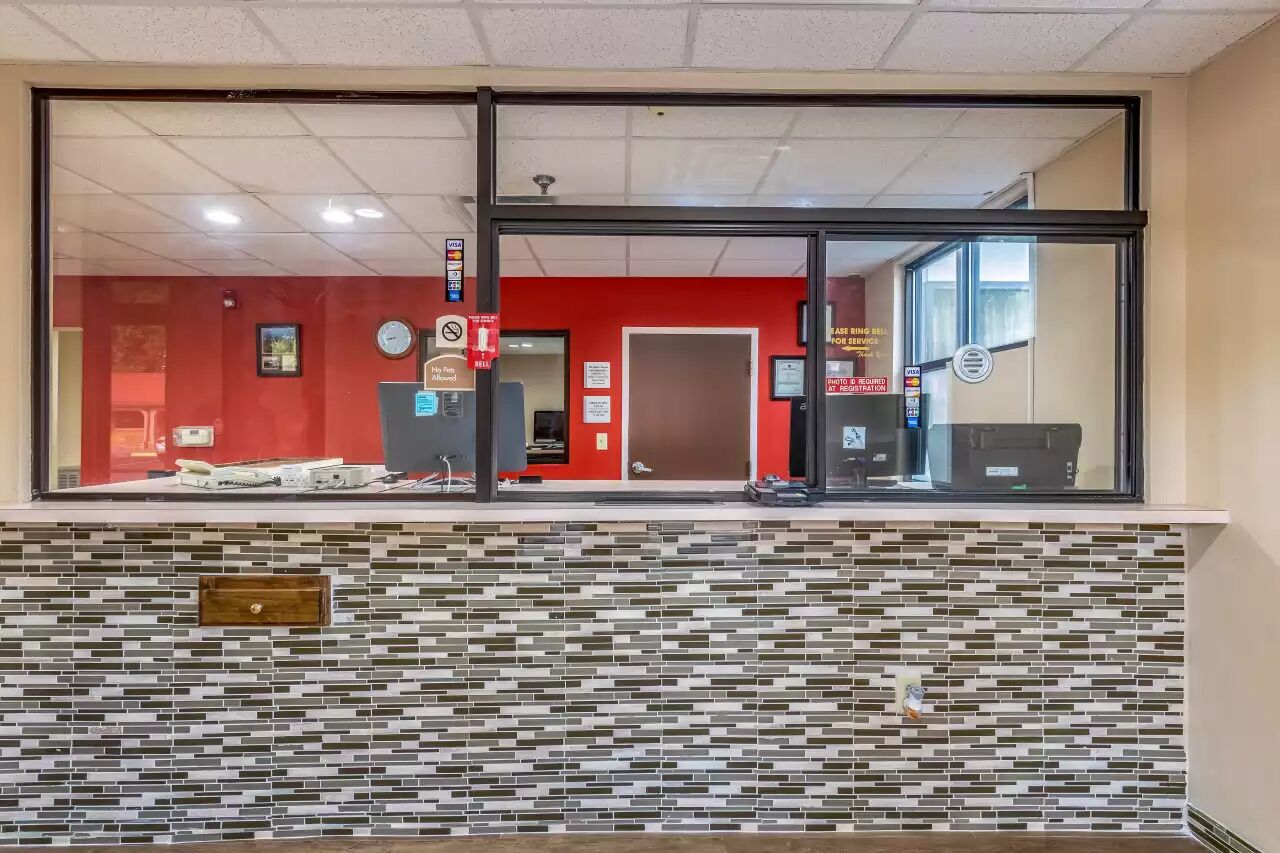 Un espace d’accueil avec un mur carrelé, un mur rouge et une porte en verre.