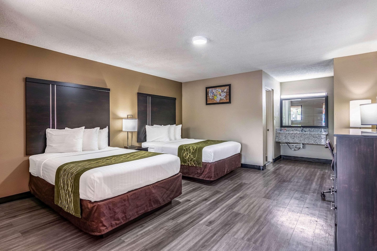 A hotel room with two beds, a bathroom, and a small kitchenette.