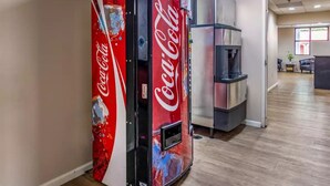 Una macchina automatica di Coca-Cola in un ambiente ufficio moderno, con una reception visibile sullo sfondo.