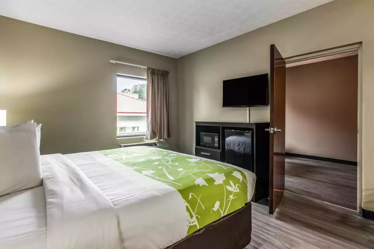 A hotel room with a bed, a television, a wardrobe, and a window with curtains.