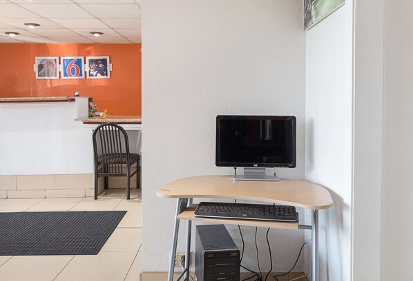 A hotel reception area with a desk, computer, and chair.