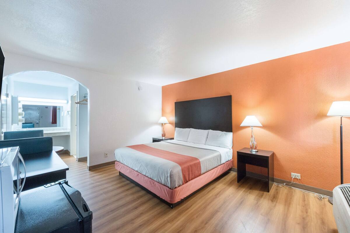 A hotel room with a bed, two bedside lamps, a desk, and a chair.