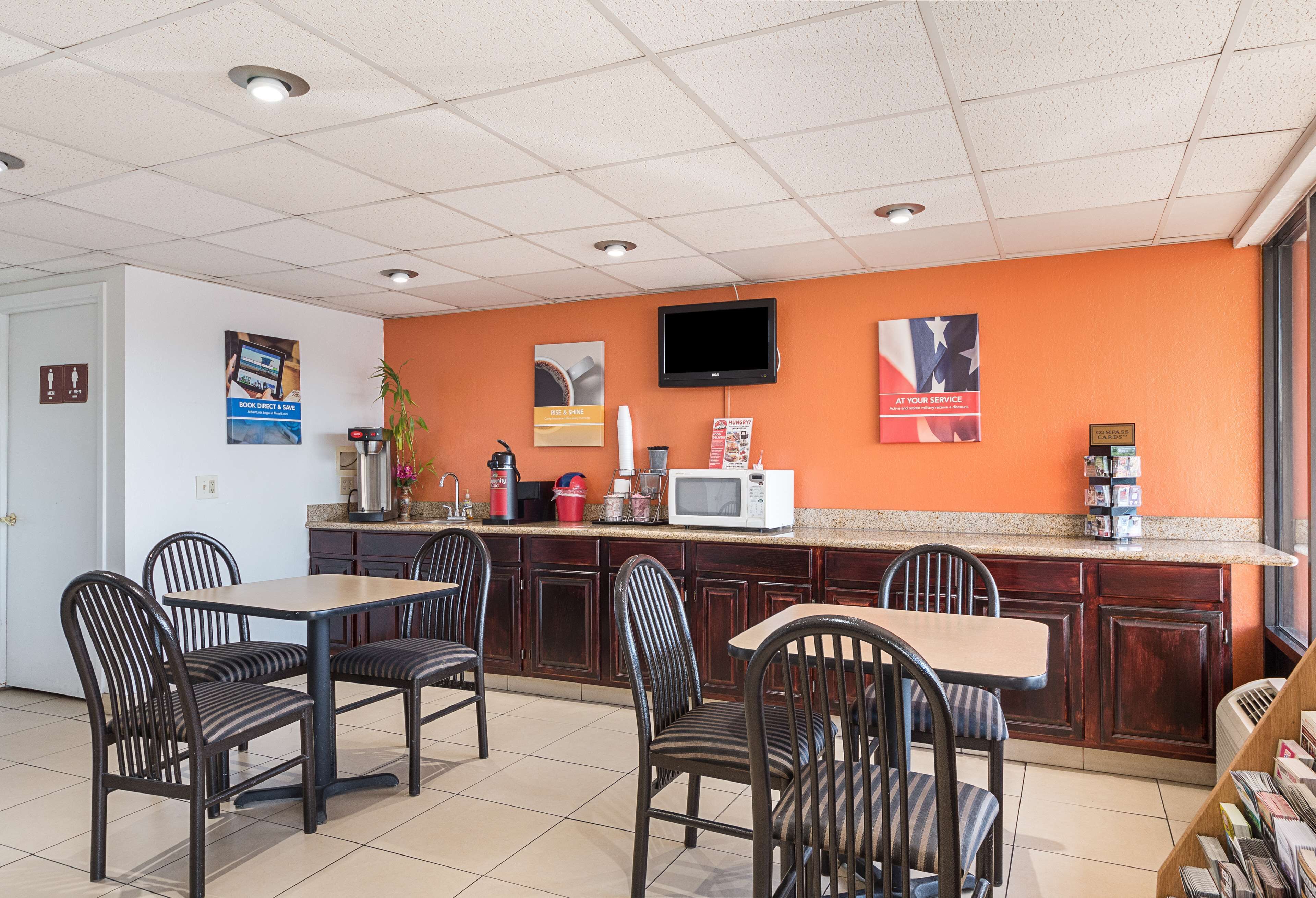 A restaurant with a counter, chairs, and a television.