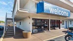 Un edificio con un letrero que dice 'Welcome', un acceso cubierto, una escalera y una motocicleta estacionada.