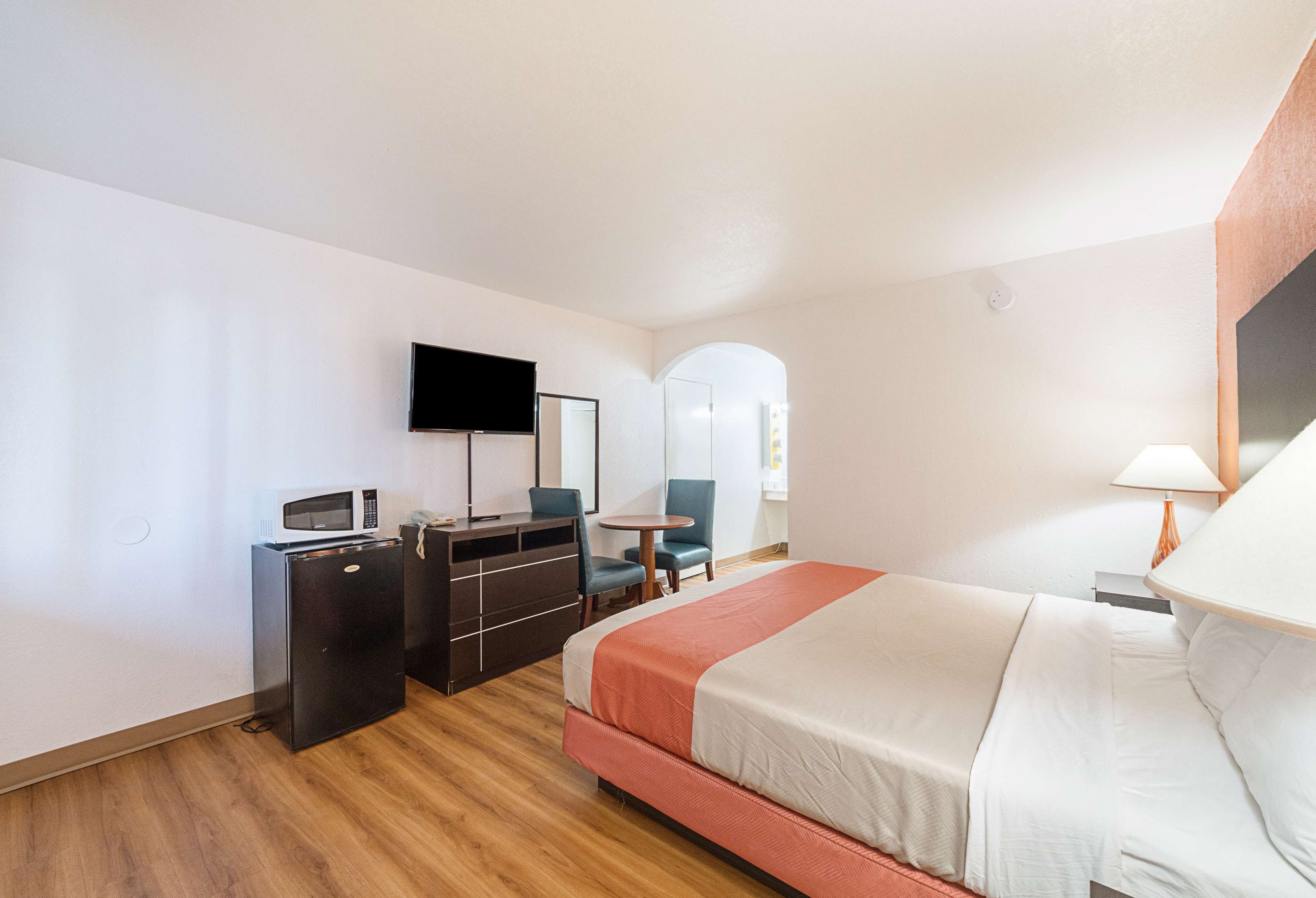 Une chambre d’hôtel comprenant un lit, un bureau avec un micro-ondes, une télévision, une chaise, une petite table et une lampe.