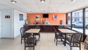 Un restaurante con mostrador, sillas, televisor y vista a la calle.