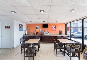 Un restaurante con mostrador, sillas, televisor y vista a la calle.