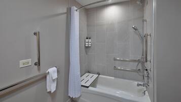 A modern bathroom with a walk-in shower, a bathtub, a towel rack, and a hand dryer.