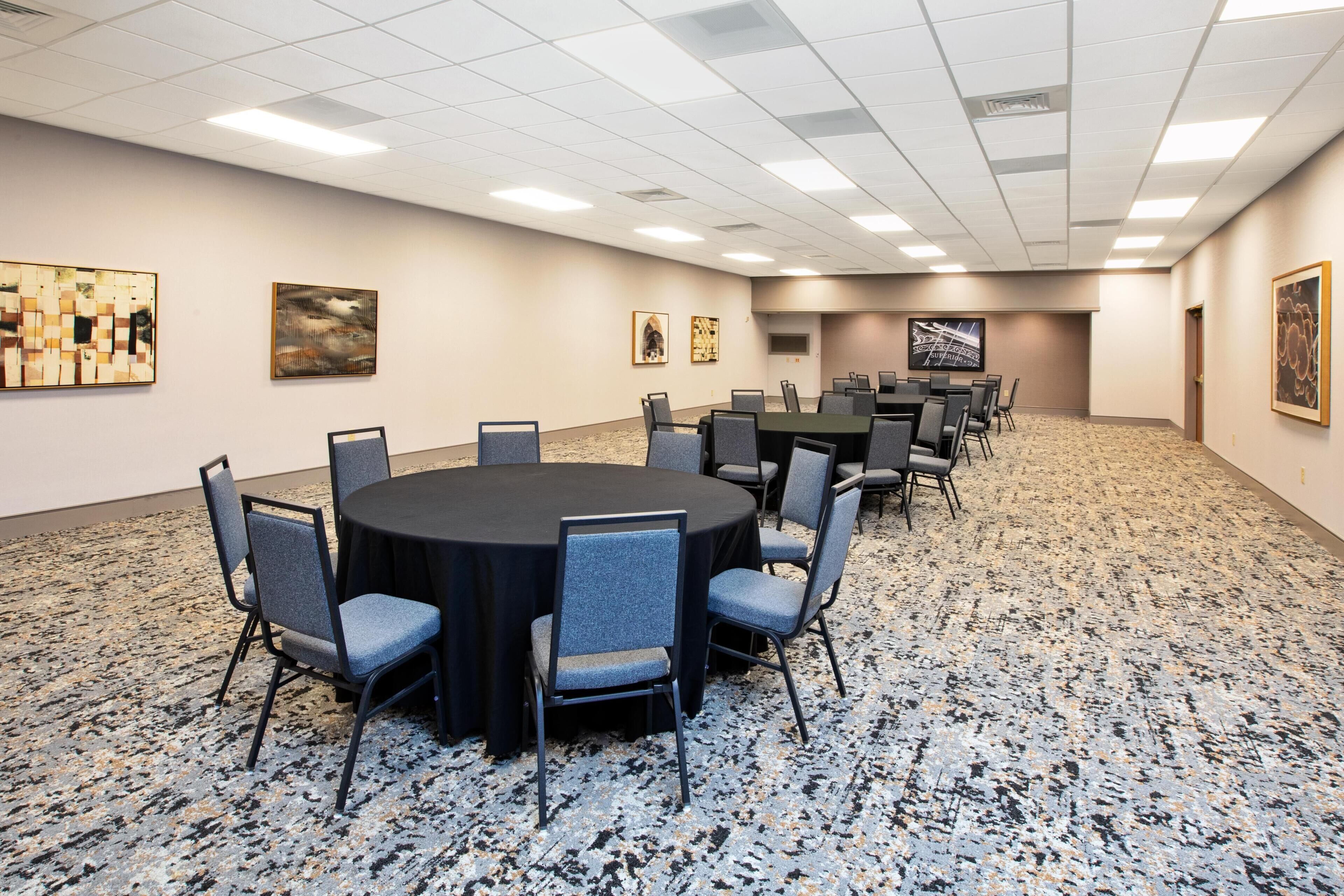 A conference room with a round table, chairs, and artwork on the walls.