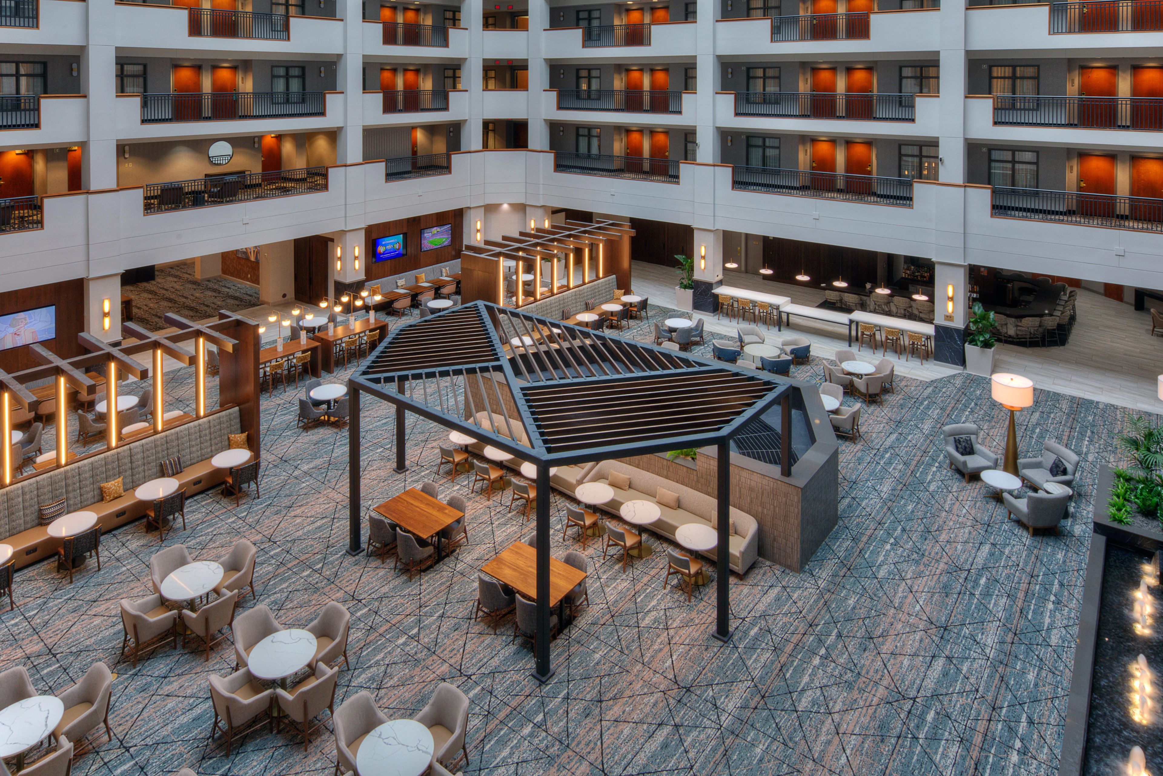 A multi-level hotel lobby with a central open space, seating areas, and a bar.
