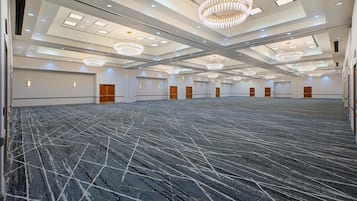 A large conference room with a high ceiling, multiple chandeliers, and a patterned carpet.