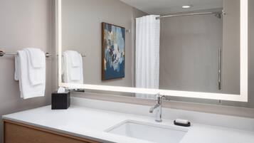 Une salle de bain moderne avec un grand miroir, un lavabo blanc et un espace douche.