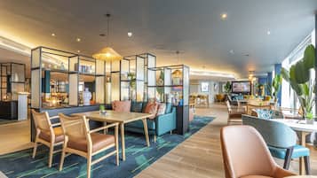 Un moderno vestíbulo de hotel con zona de estar, un bar y una recepción.