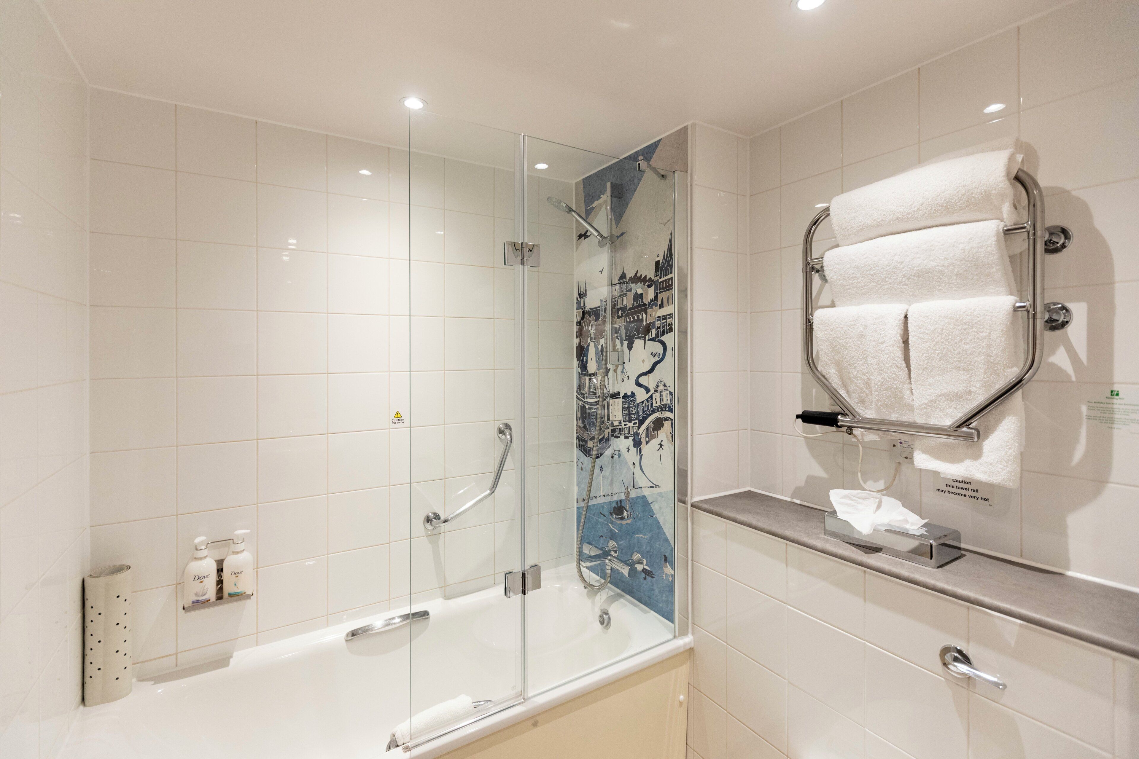 Un bagno moderno con box doccia in vetro, una vasca da bagno e un portasciugamani.