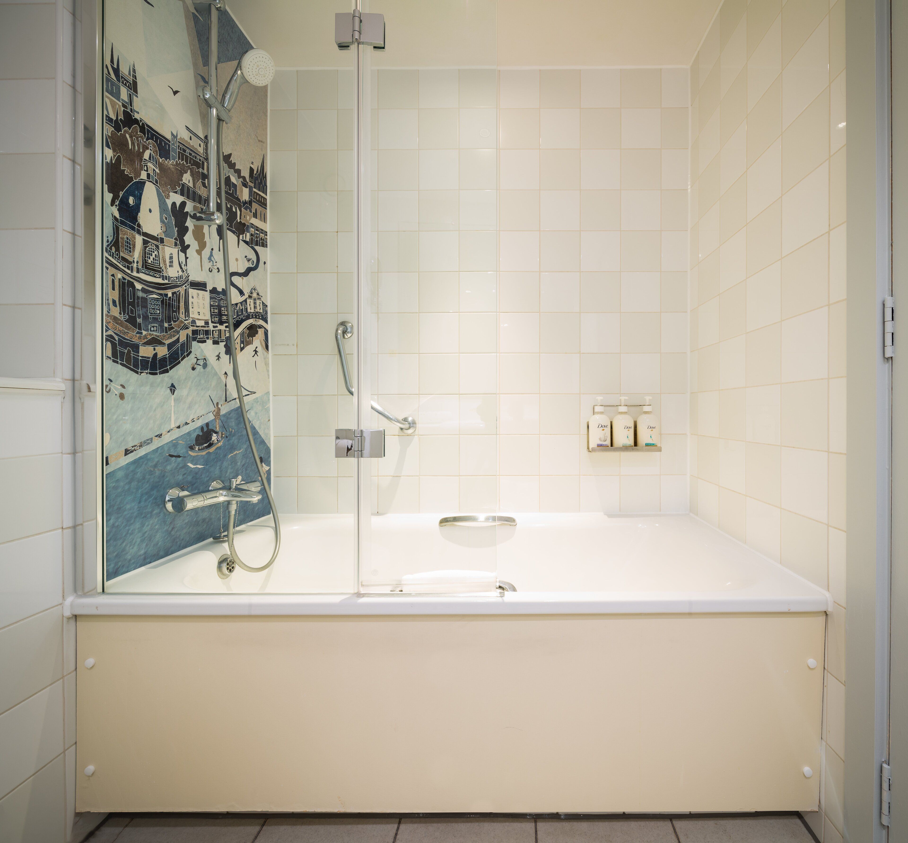 A bathroom with a bathtub, a shower, and a tiled wall with a cityscape mural.