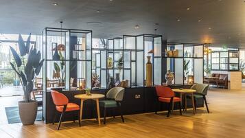Een modern interieur met een zithoek, voorzien van een glazen scheiding, houten vloer en diverse decoratieve elementen.