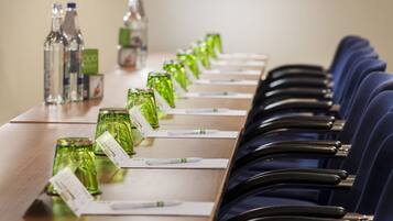 A conference table with chairs, green glass bottles, and name cards.