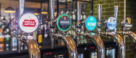 Fila de grifos de cerveza con etiquetas que incluyen Stella Artois, Beck's, Mellow, Revell y Guinness.