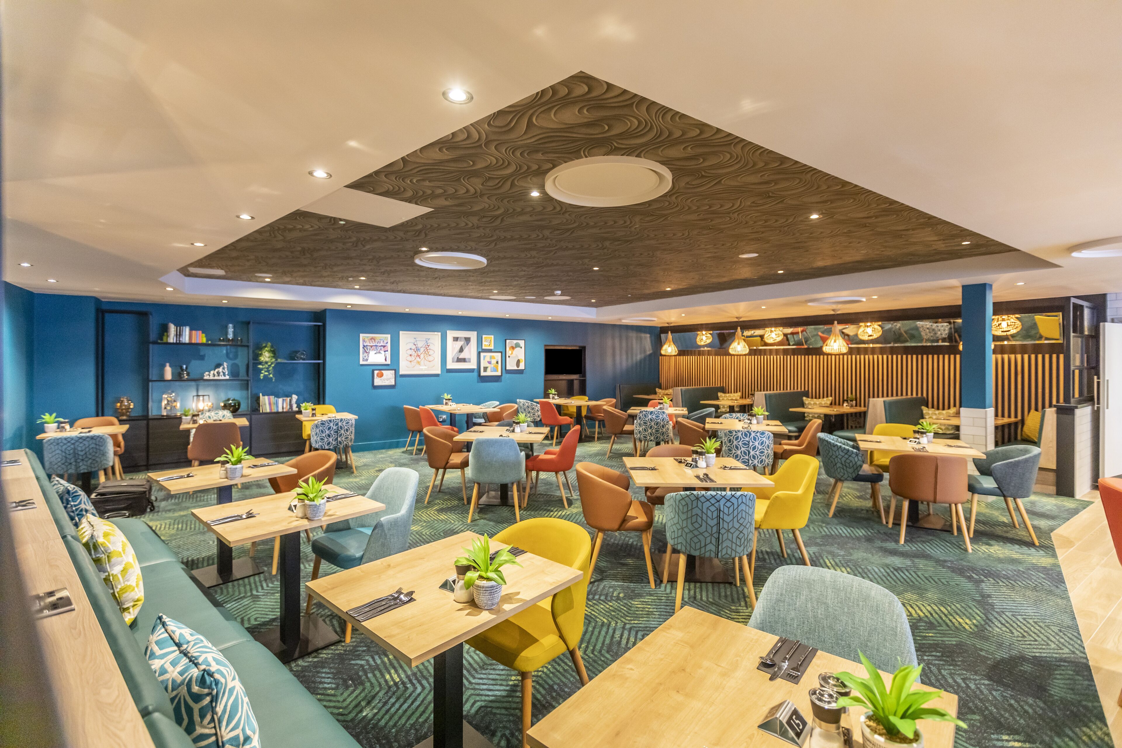 Un restaurante moderno con diferentes opciones de asiento, como cabinas, mesas y taburetes altos.