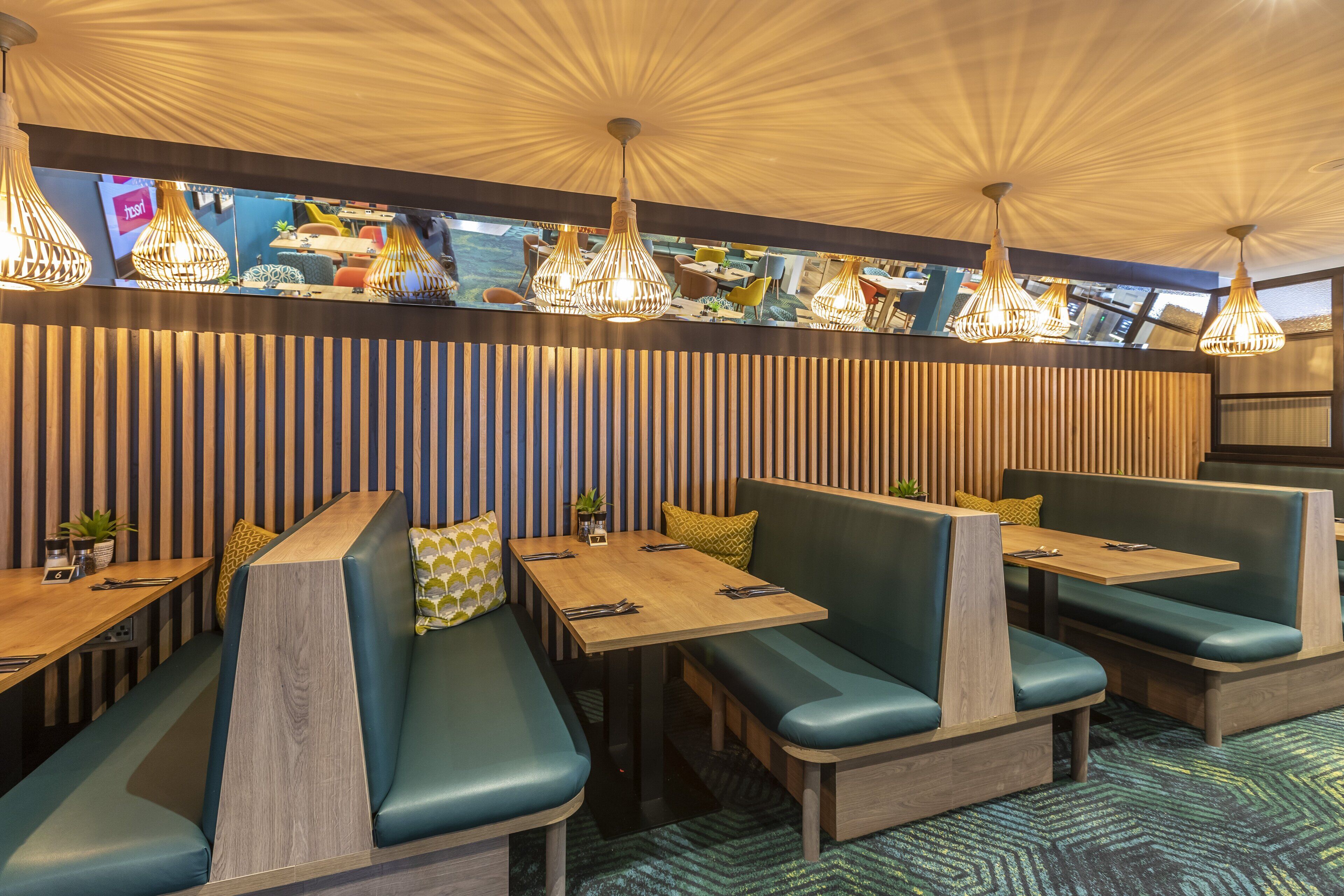 A restaurant with booth seating, wooden tables, and hanging pendant lights.