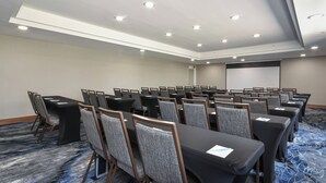 A conference room with rows of tables and chairs, a projector screen, and recessed ceiling lights. - Fairfield by Marriott Inn & Suites Columbia Harbison (Columbia)