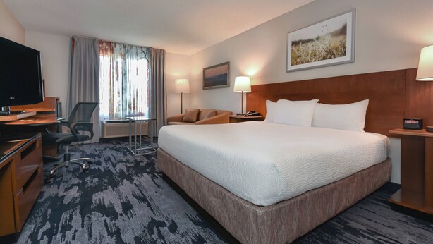 A hotel room with a large bed, a desk with a computer, a chair, a TV, and a window with curtains. - Fairfield by Marriott Inn & Suites Columbia Harbison (Columbia)