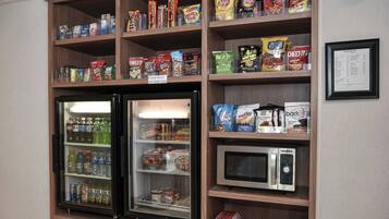 Una exhibición de snacks y bebidas, con un microondas y un refrigerador.