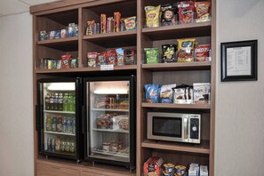 A snack and beverage display with a microwave and a refrigerator. - Fairfield by Marriott Inn & Suites Columbia Harbison (Columbia)