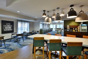 A hotel dining area with a large table, chairs, and pendant lighting. - Fairfield by Marriott Inn & Suites Charlottesville North (Charlottesville)