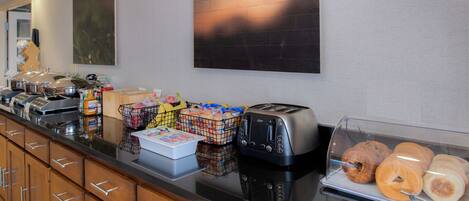 A breakfast buffet with various food items, a toaster, and a coffee machine.