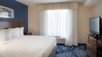 A hotel room with a large bed, a television, a nightstand, and a window with curtains.