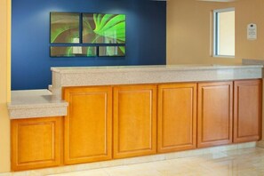 A reception area with a counter, wooden cabinets, and a blue wall with abstract art.