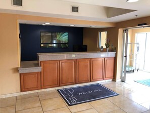 A kitchen with wooden cabinets, a granite countertop, and a welcome mat. - Country Inn & Suites by Radisson, Fayetteville I-95, NC (Fayetteville)