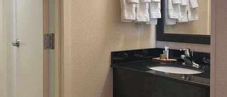 A bathroom with a white sink, black countertop, and a mirror above the sink.