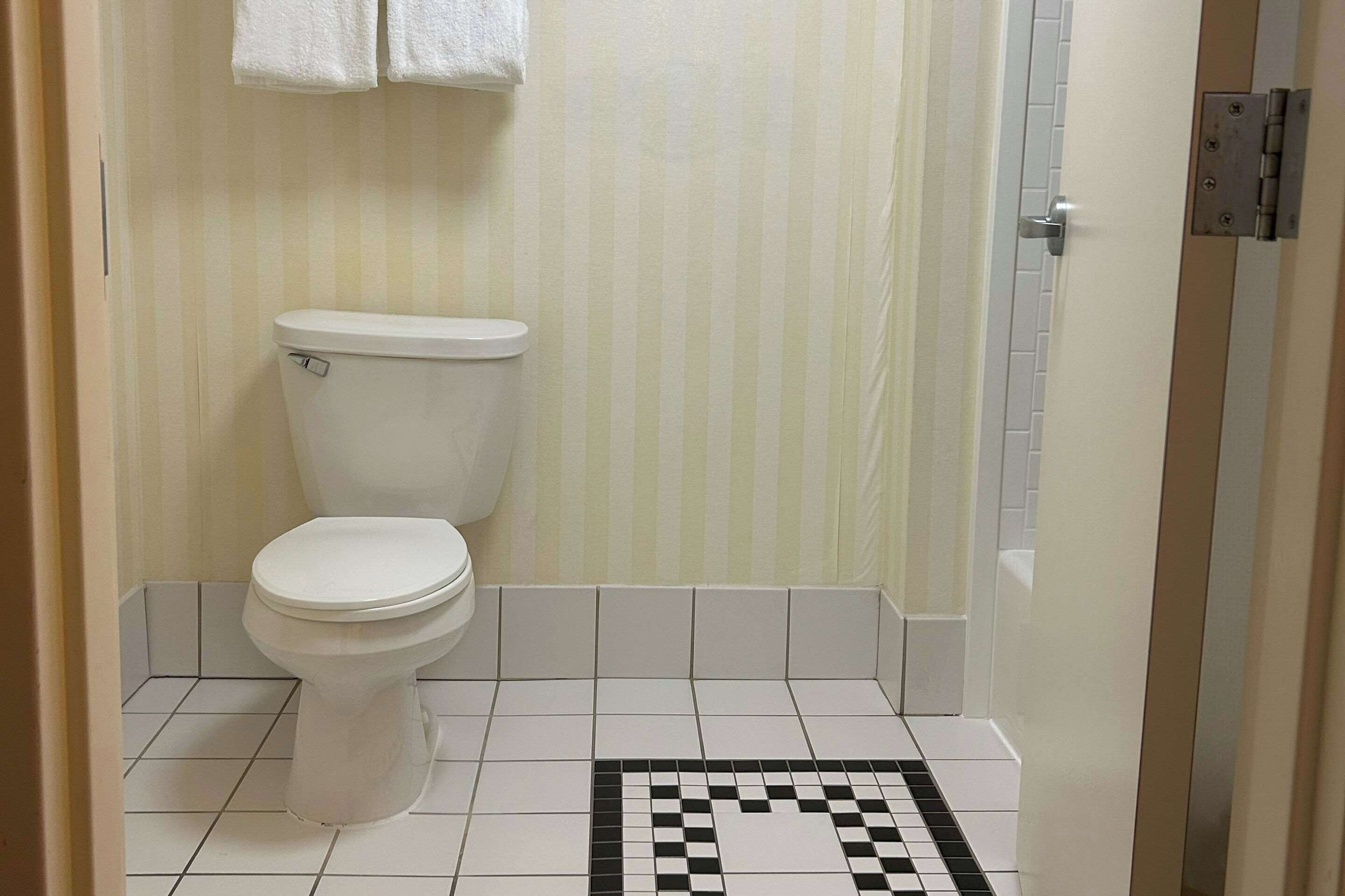 Et badeværelse med toilet, flisegulv og stribet væg.