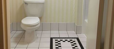 A bathroom with a toilet, a tiled floor, and a striped wall.