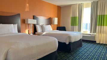 Una habitación de hotel con dos camas, una mesita de noche, una lámpara, una silla y una ventana con cortinas.