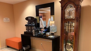 Ein Hotelzimmer mit einer Kaffeestation, einer großen Uhr und einem Mülleimer.