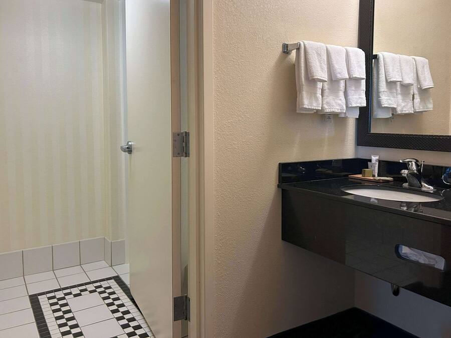 A bathroom with a shower, toilet, sink, and a mirror.