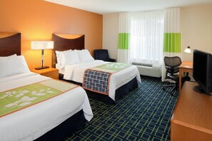 A hotel room with two beds, a desk with a computer, a chair, and a window with curtains.