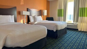 Ein Hotelzimmer mit zwei Betten, einem großen Fenster mit Vorhängen, einem Flachbildfernseher und einem Wandheizkörper.