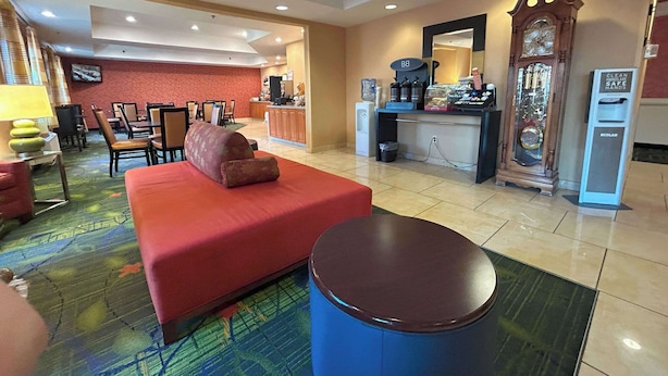 Eine Hotelhalle mit einem roten Sofa, einem blauen Hocker, einer großen Uhr und einer Kaffeestation.