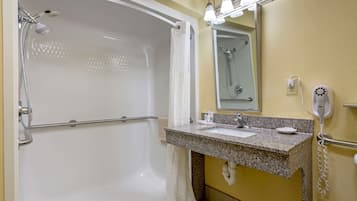 A bathroom with a bathtub, a sink with a mirror, and a hairdryer on the wall.